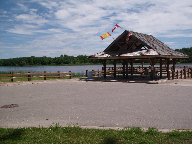 <div class="text-large">a gazeebo like hut with a street infront of it and a lake behind it</div>