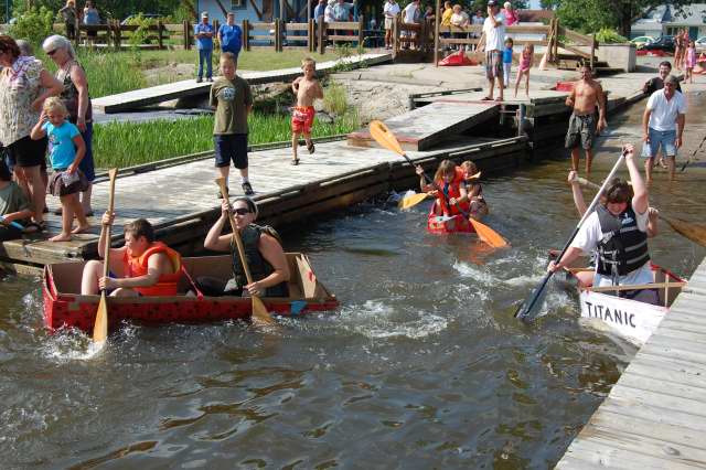 <div class="text-large">2 boats with 2 people each holding oars leaving a dock</div>