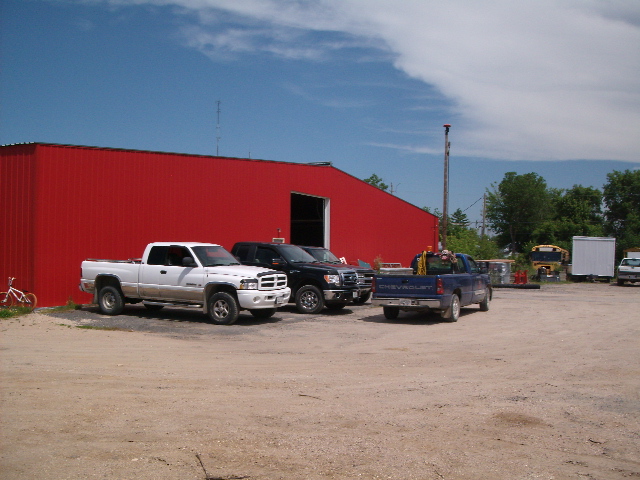 a red garage with 4 pick-up trucks in front of it