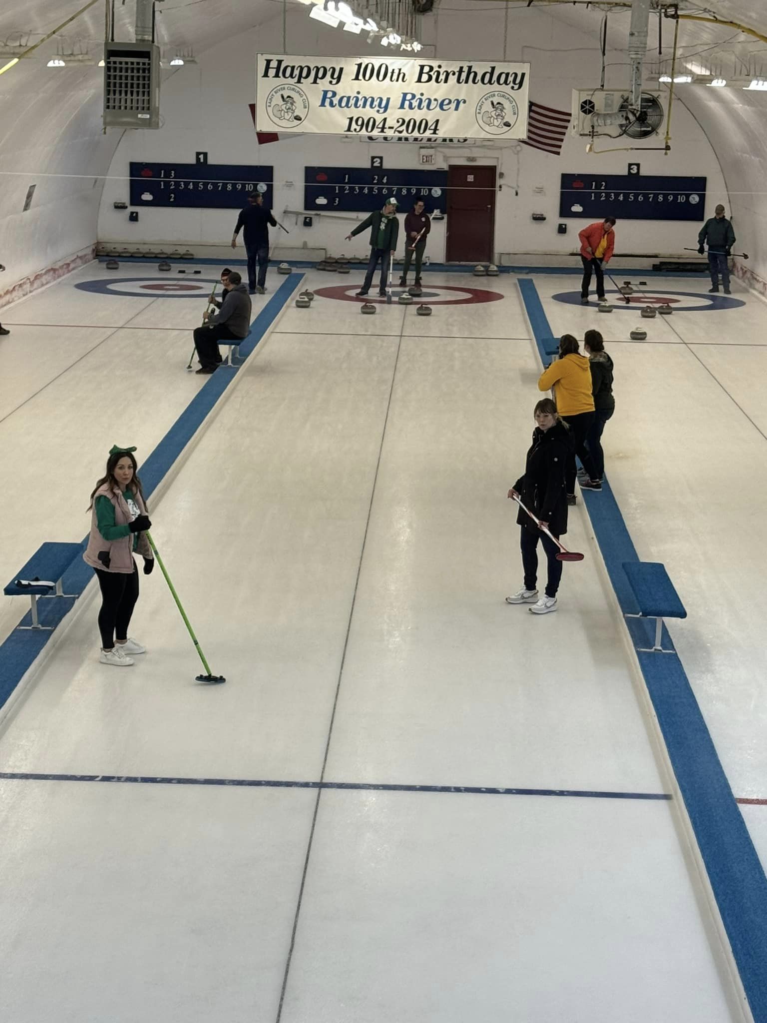 3 lanes in the curling rink with people on either ends