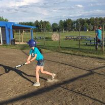 a girl with a baseball bat getting ready to hit the ball