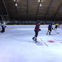 3 people playing hockey in an inside rink