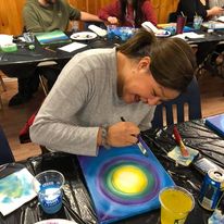 a woman painting a yellow circle with a blue background