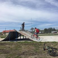 a 2 sides ramp with 1 guy on top and another guy on a bike doing a trick on the ramp