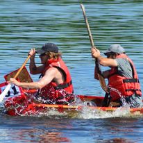 2 men on a boat with oars rowing