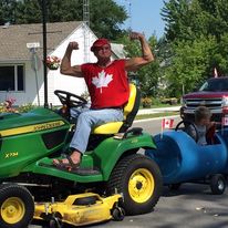 man flexing biceps on top of a tractor