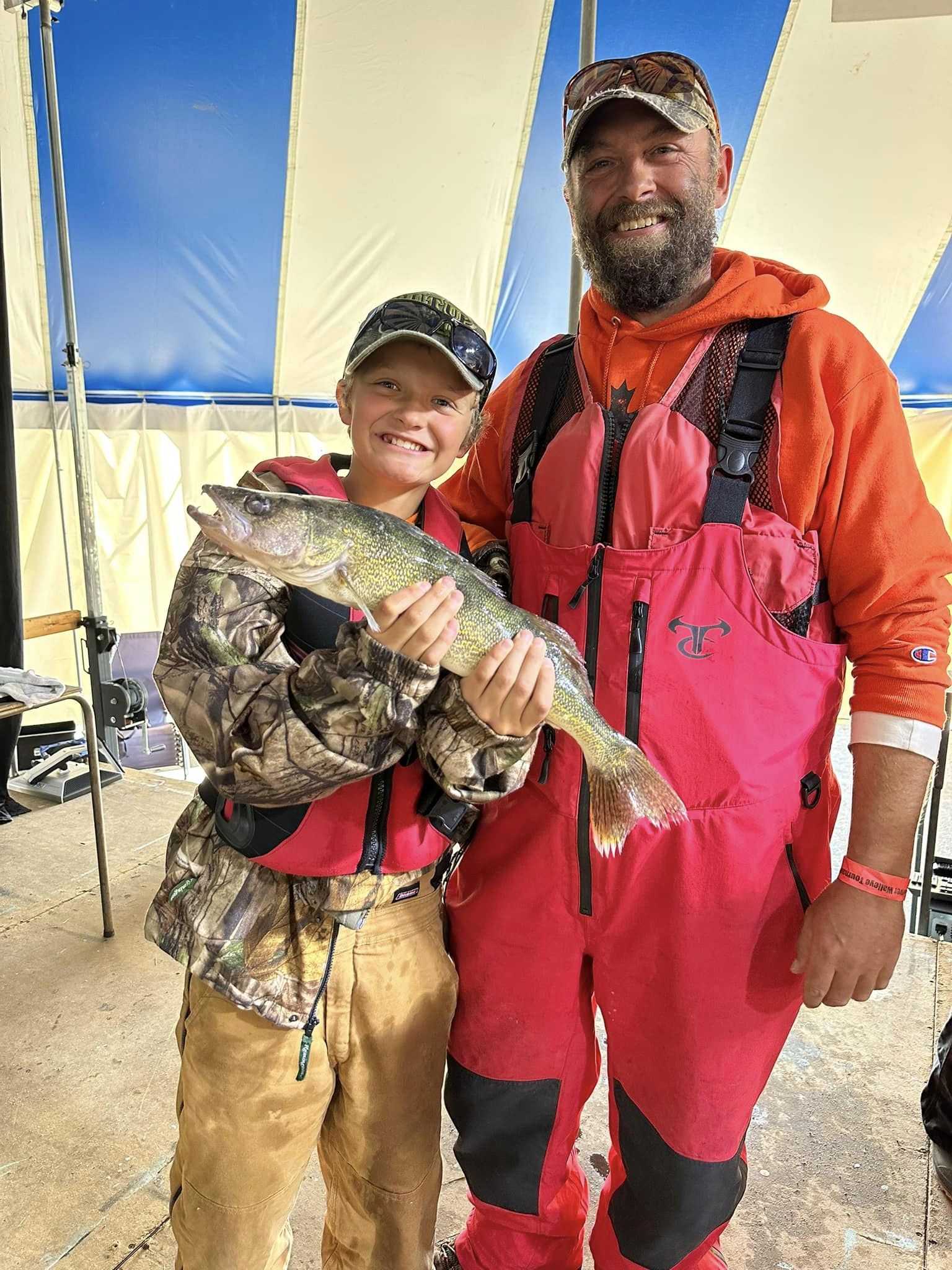a male kid and a grown man holding up a walleye