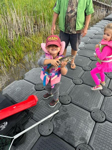 little boy holding up a small walleye little girl in a pink outfit standing beside grown man standing behind