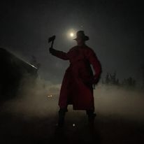 silhouette of a man in a trench coat and a hat holding an axe