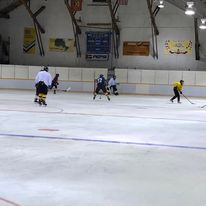 5 people playing hockey in an indoor rink